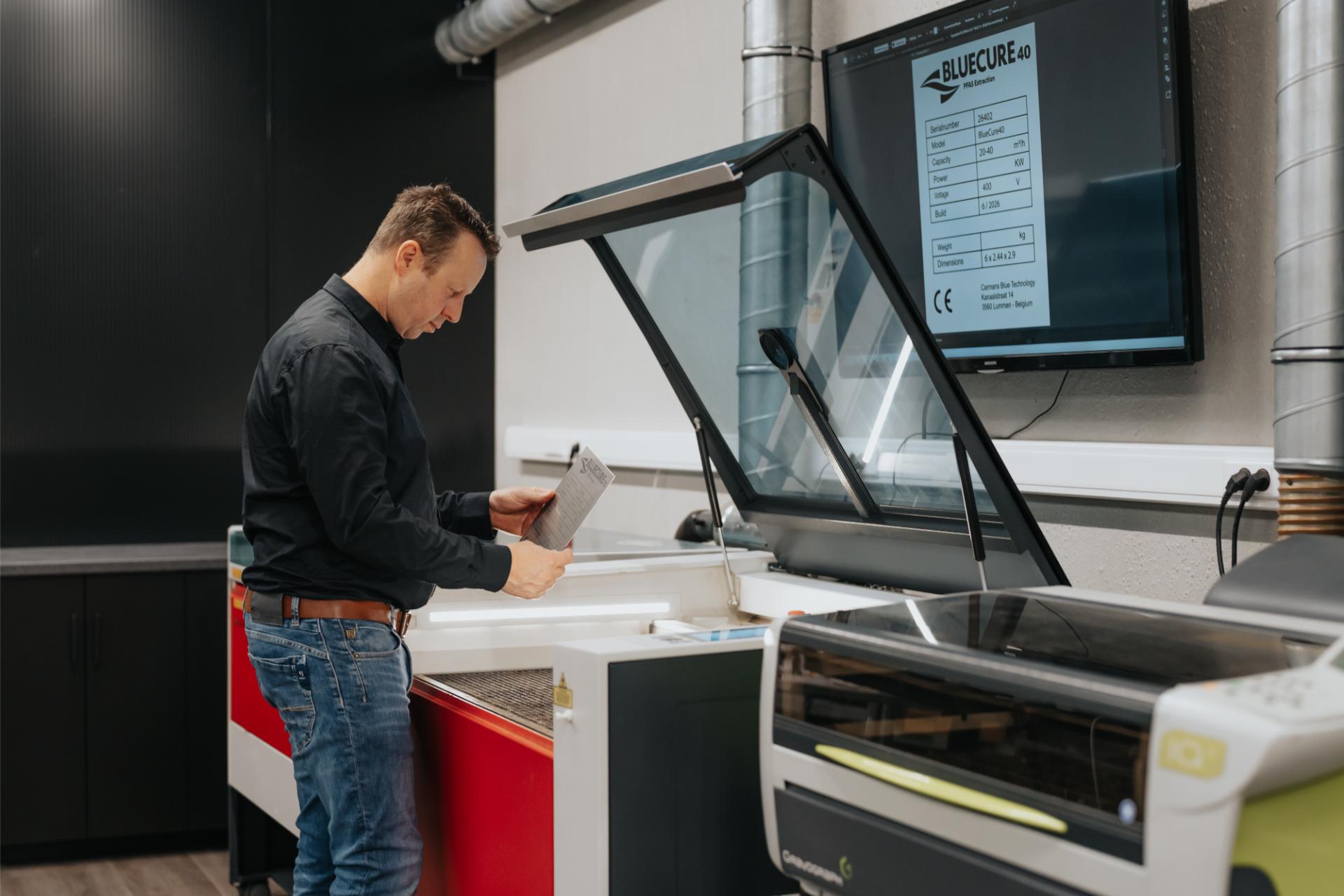 Wouter aan het werk bij de lasermachine in de werkplaats.